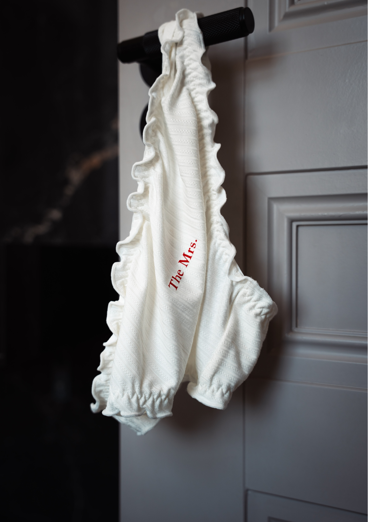 White frill knickers with 'The Mrs.' text hanging on the door handle of hotel bedroom